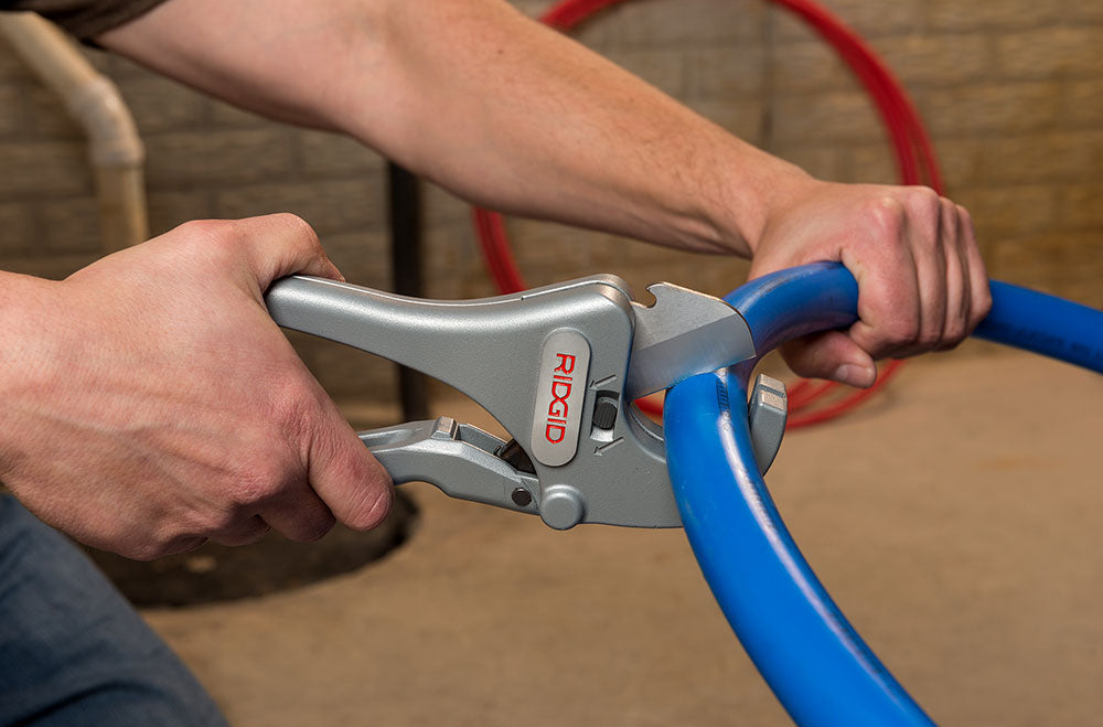 Professional plumber using a tubing cutter to create a clean square cut on a copper pipe.