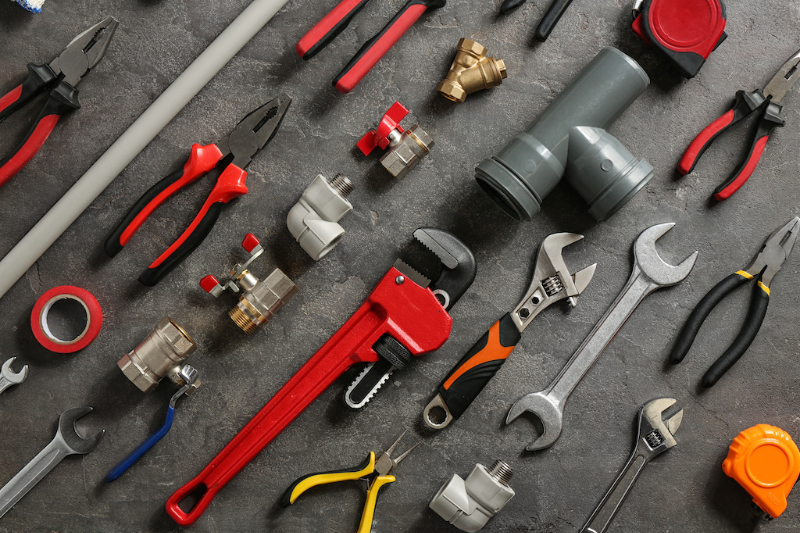 Top essential plumbing tools for master plumbers including adjustable wrenches and water pump pliers on a workbench.